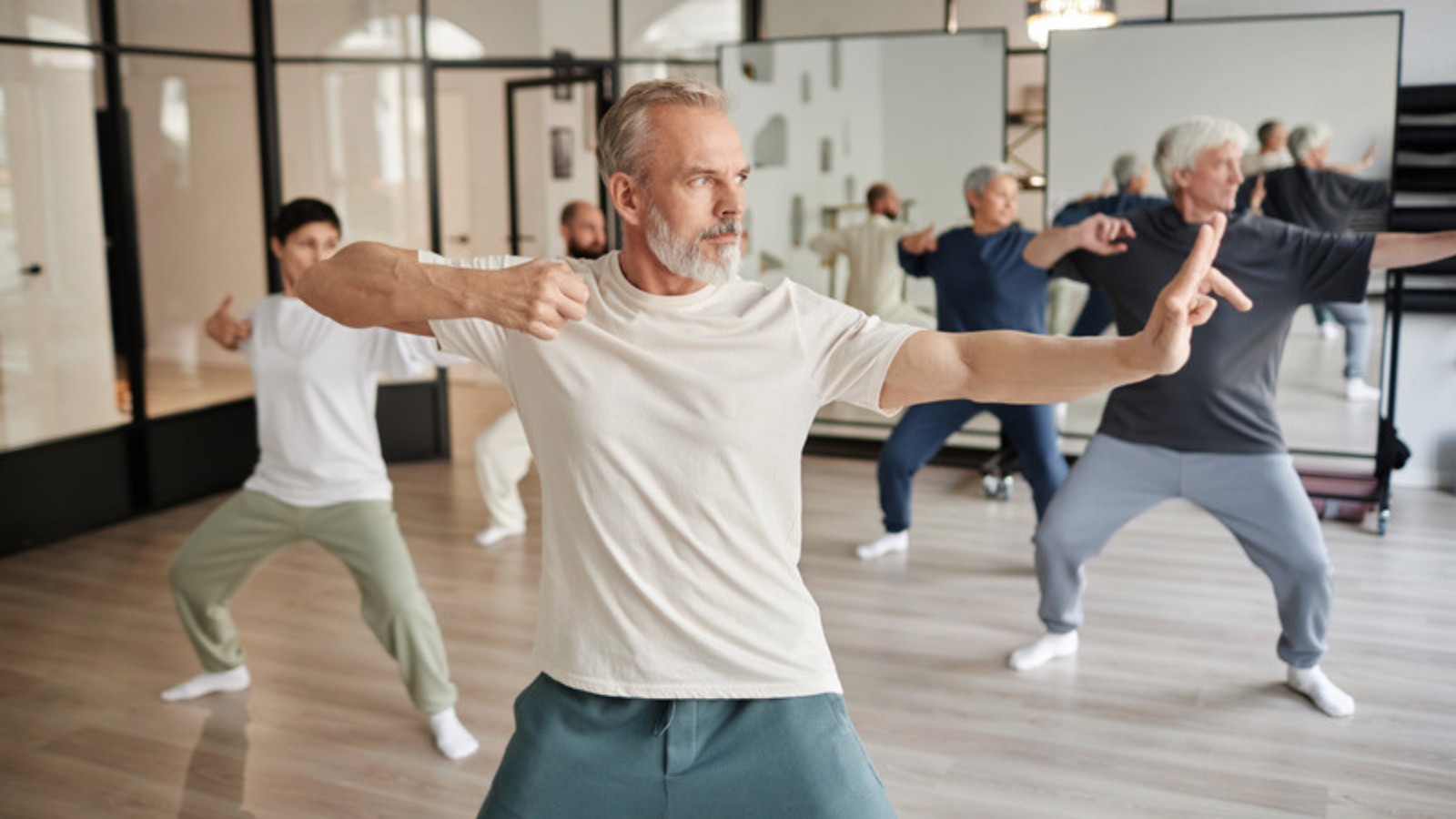 Cours de qigong en studio, pratiquants de tous âges en mouvement