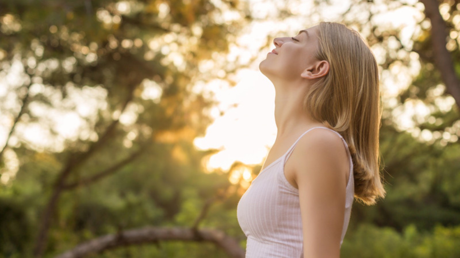 Femme respirant profondément en nature, dans la lumière dorée du soir